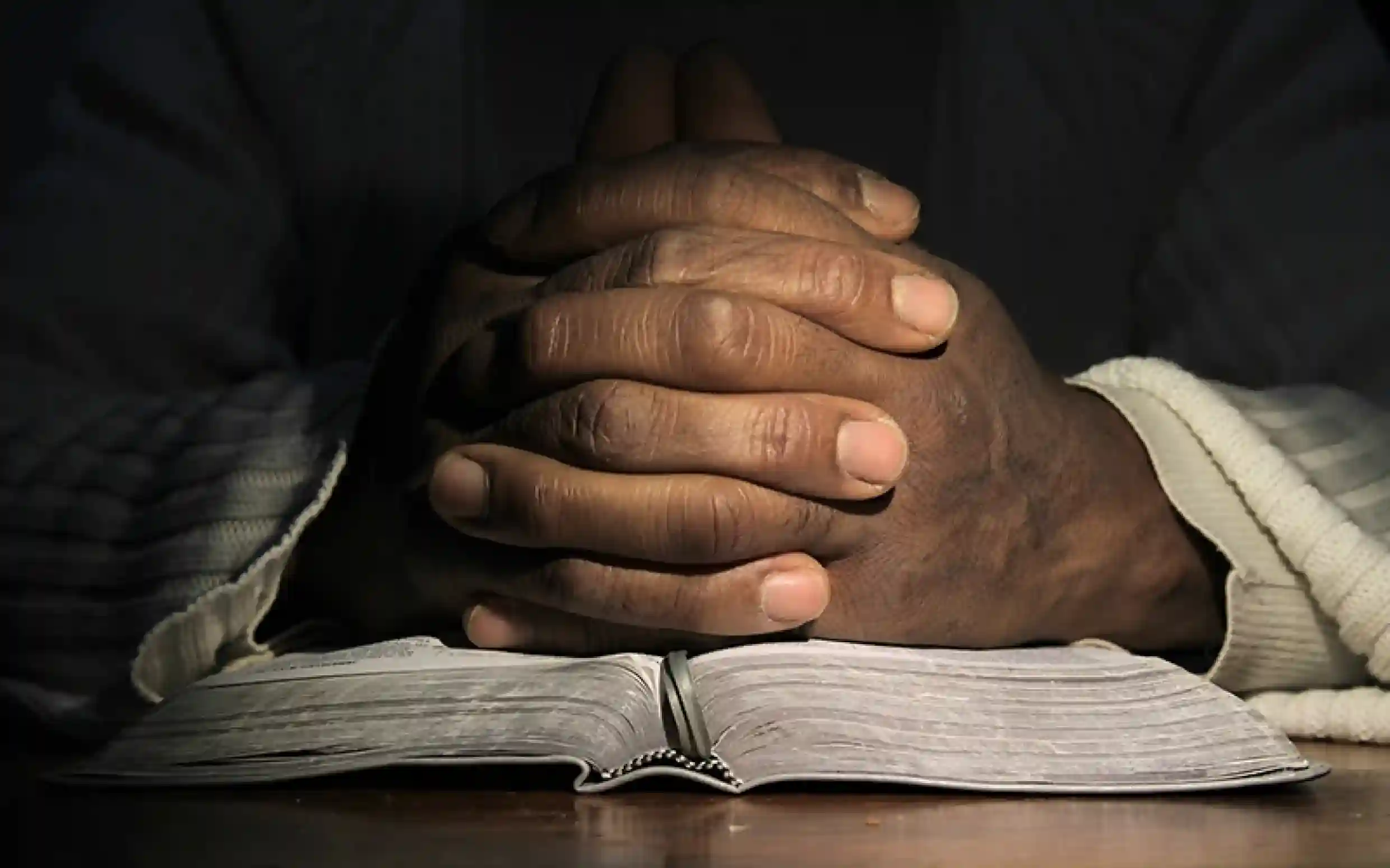 Folded hands on scriptures