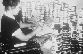 Женщина работает над съемкой бумажных документов по технологии микрофильмирования.