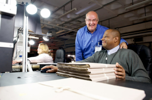 Двое мужчин улыбаются, работая над какими-то документами