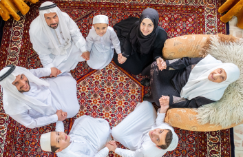 Арабская семья улыбается и держится за руки.